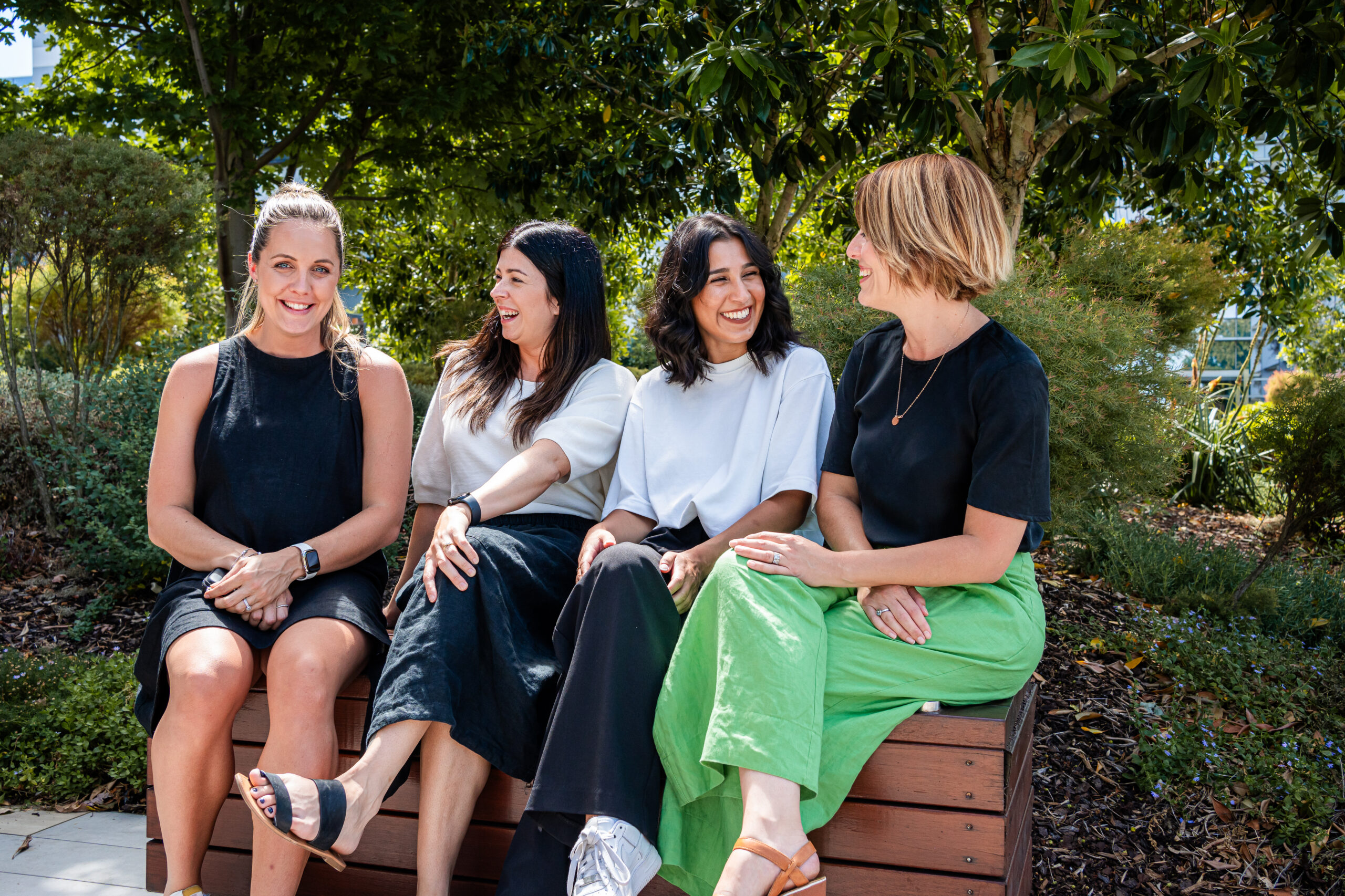 Better Health Company staff members sitting on a bench smiling.