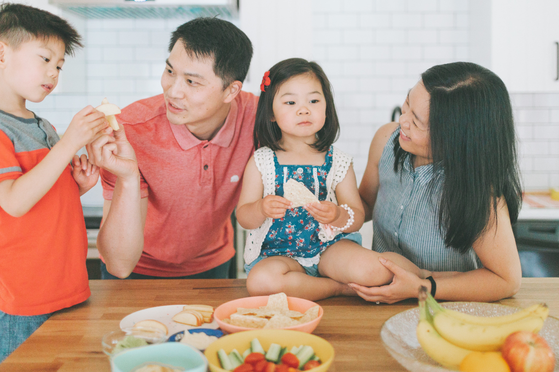 Family around the kitchen bench preparing a meal.